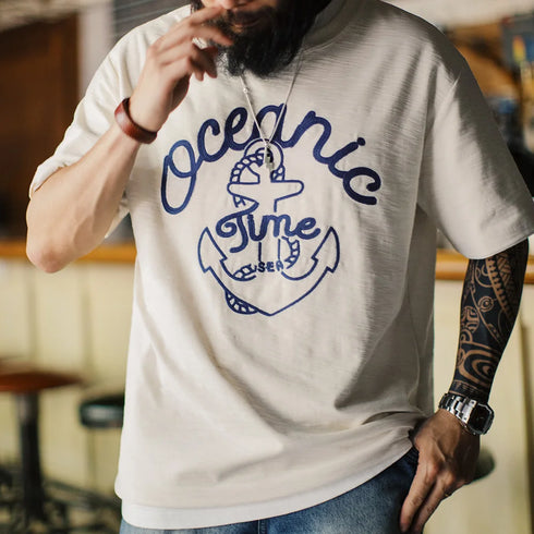 Person wearing a white t-shirt with blue graphic design and text.